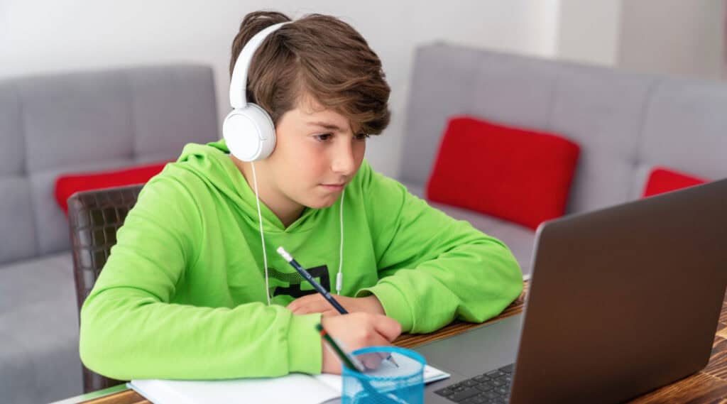 A young boy taking a class online.