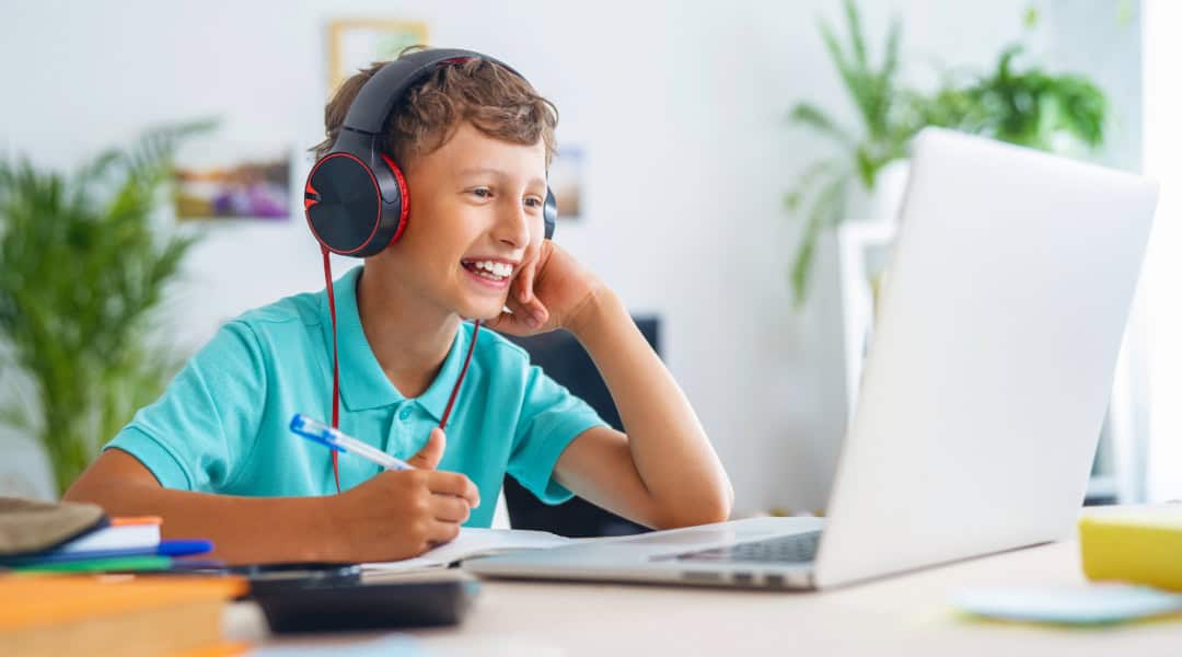A young boy engaged and happy about taking a class on Outschool.