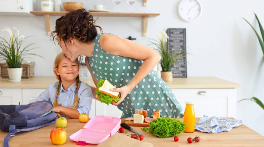 A mom and her daughter are in the kitchen doing a run through of packing lunch for school.