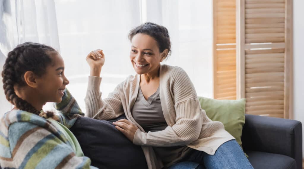 A mom and daughter sitting on the couch discussing feelings.