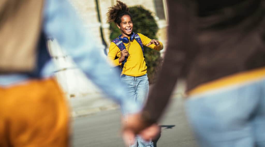 A young girl happy to be visiting her school with her parents before classes start. Add this to your list of back to school tips for families.