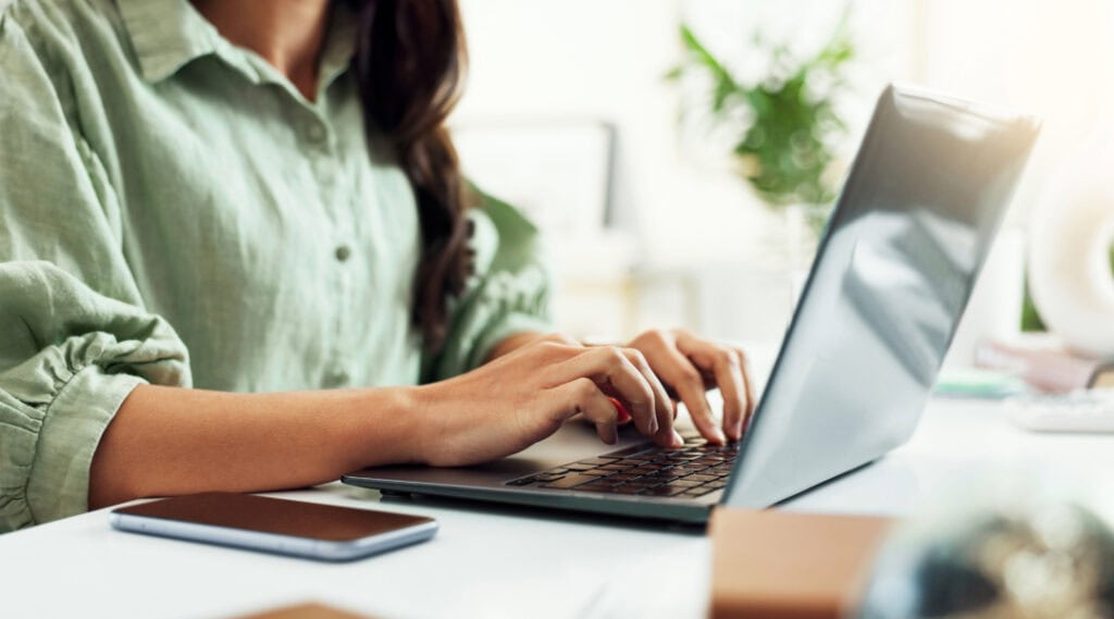 A picture of a woman typing on a laptop. Advice from a teacher - send families a heartfelt email during the summer months.