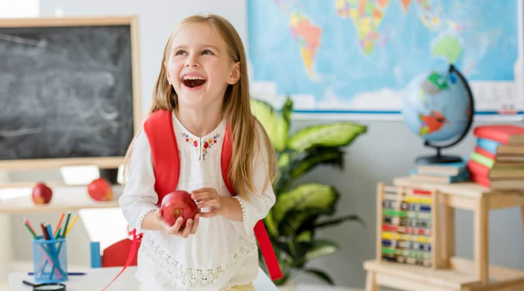 A picture of a happy young girl in her classroom. Advice from a teacher says taking small steps to ensure comfort makes back to school a happy time.