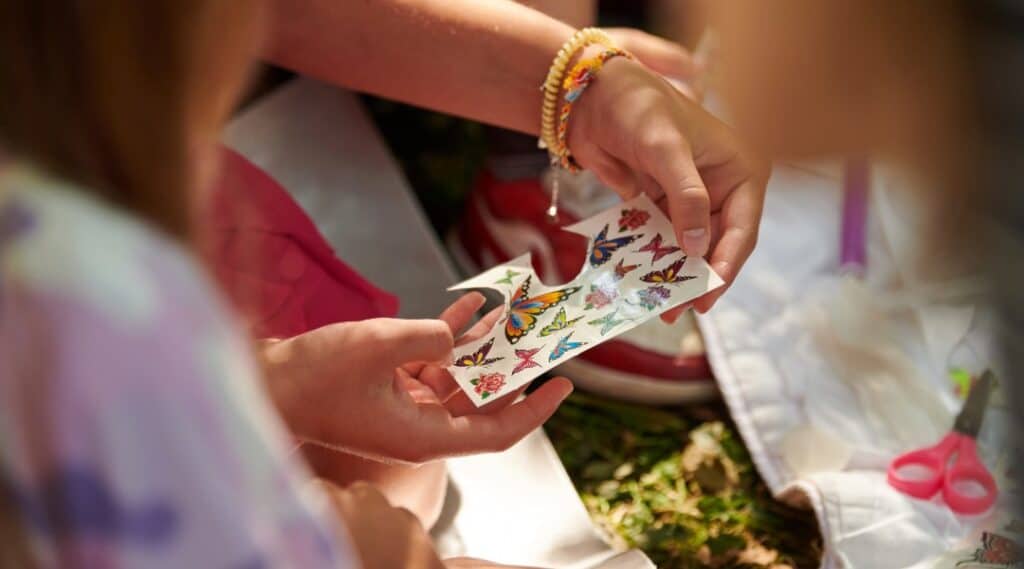 The hands of two children looking at their sticker collection.