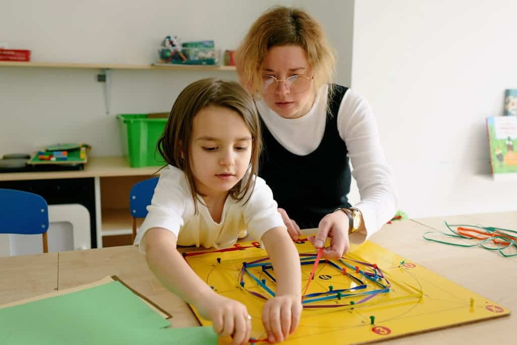 A child and teacher work together on an educational game in a classroom setting.