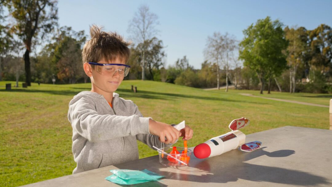 A child outdoors conducting a science experiment with a toy rocket that he built using a subscription box.