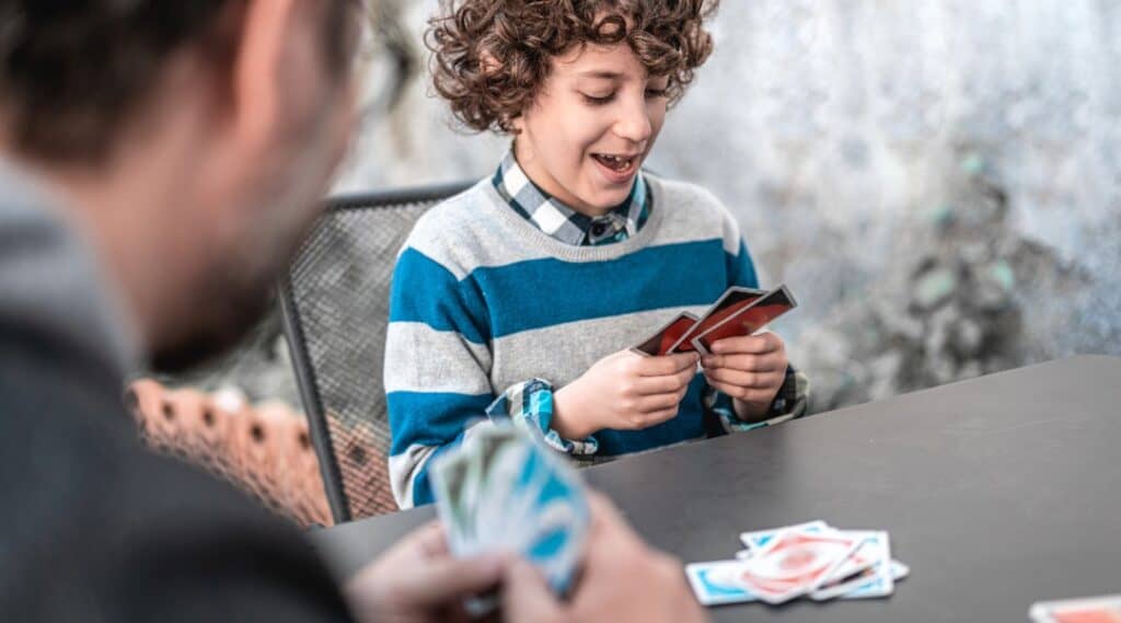 A father and son are playing Uno. This is one of the best math card games for kids.