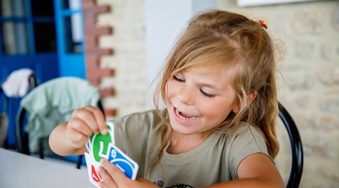 A young girl engages in Uno, a great math card game for kids.