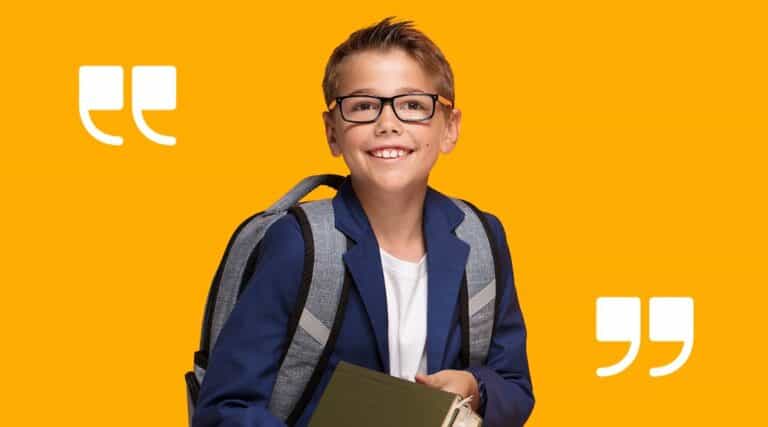 A young boy in a blazer and wearing a backback holding books.