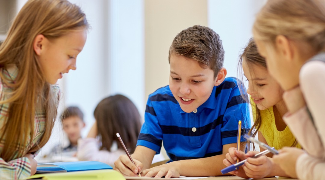 A picture of kids working together solving math riddles using a 100 chart.