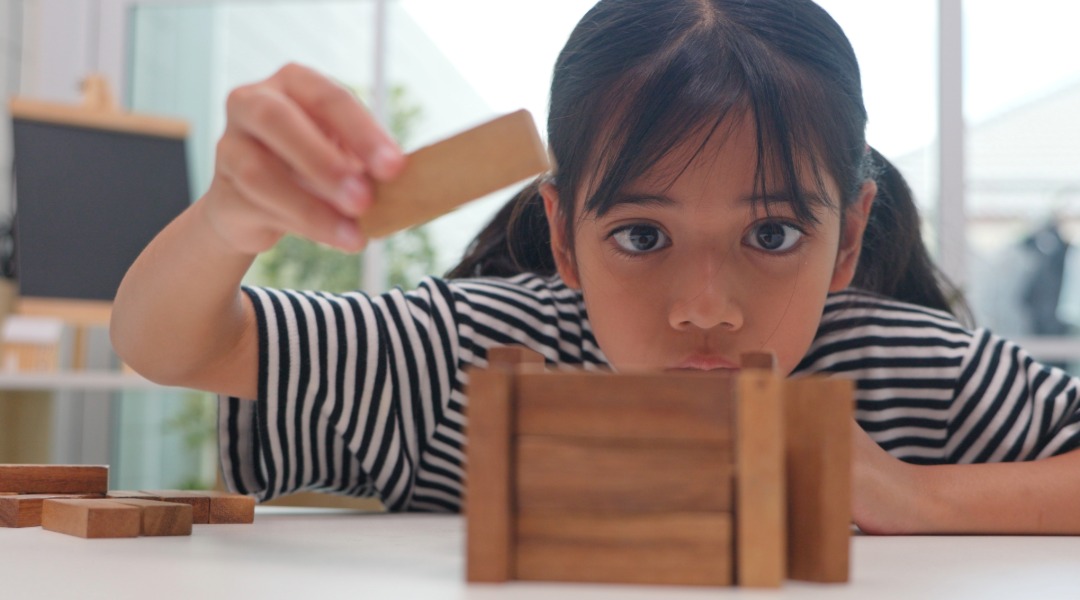 A young girl building something with 100 blocks as an activity for the 100th day of school. She looks very focused.
