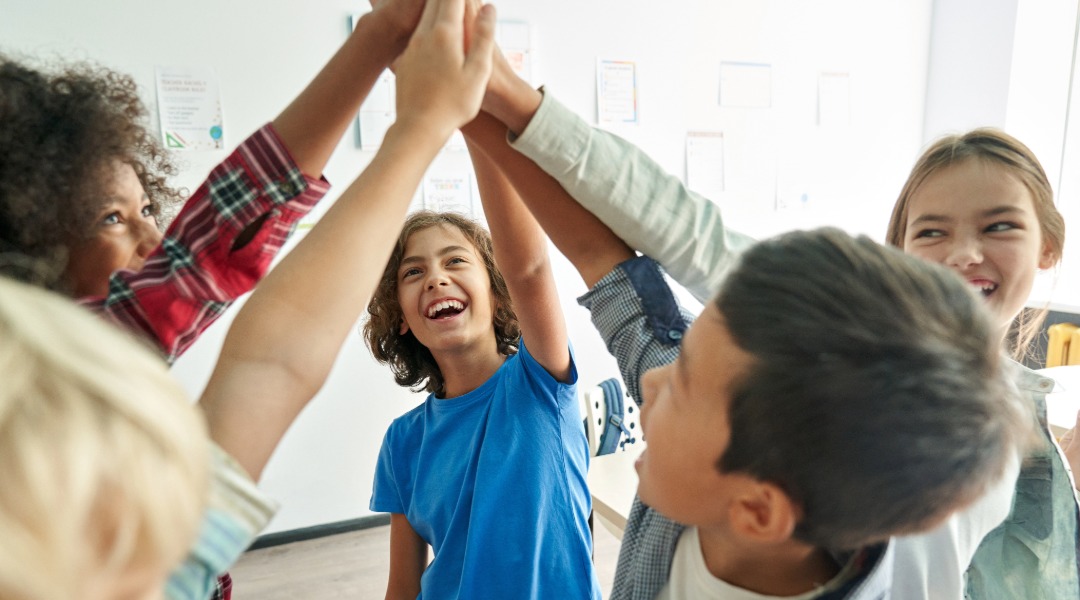 An image of a group of children giving a group high five.