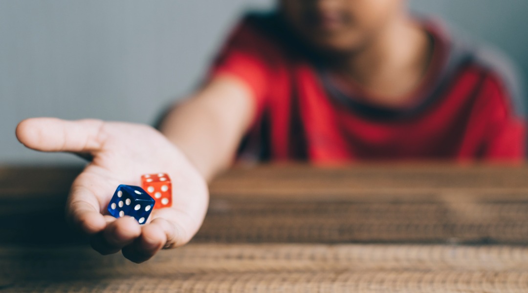A picture of a young childs arm outstretched palm open showing two dice. Dice games are always a great choice for a 100th day of school activity. 