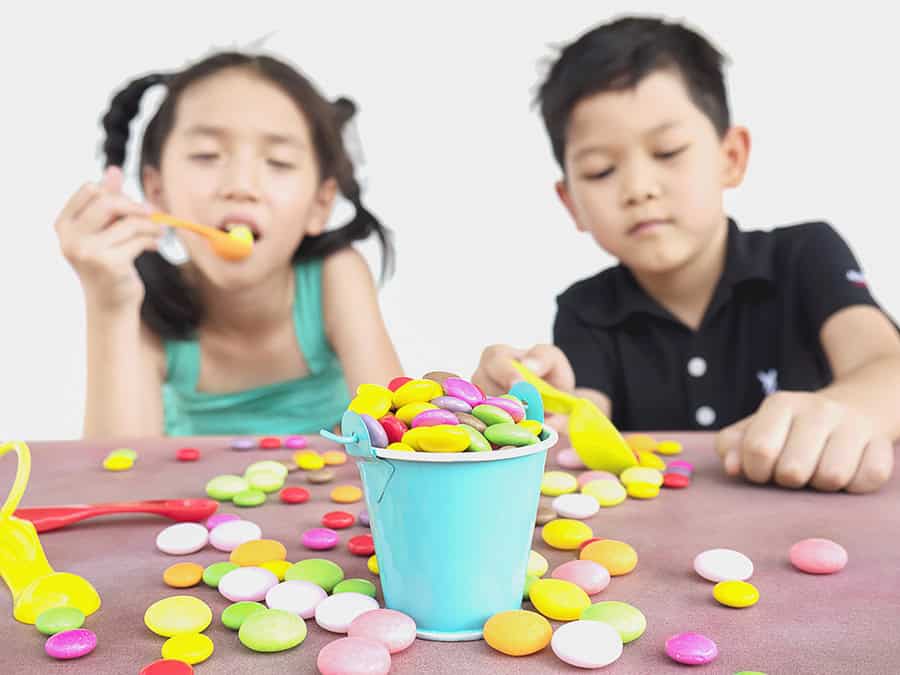 Asian kids are playing with candy. Photo is focused at candy.