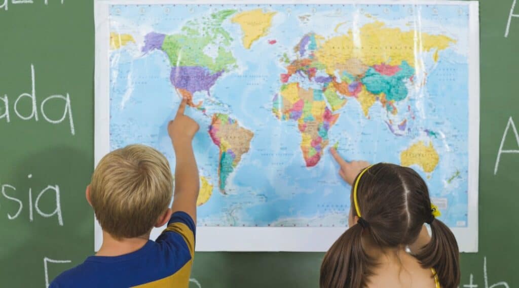 Grammar games can involve Geography too! In this image, two students are pointing at a map. 