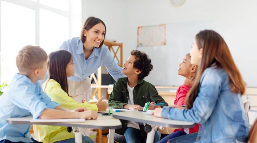 A small group of elementary students working together to play a fun word association game while a teacher looks on.