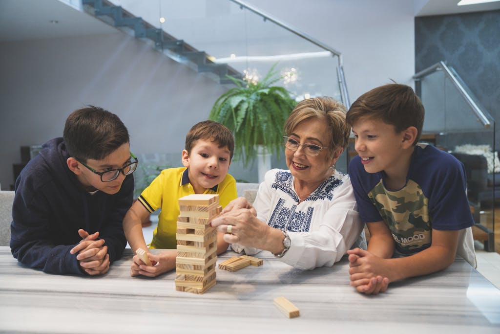 A fun classroom moment with a teacher and 3 elementary aged boys playing Jenga indoors.