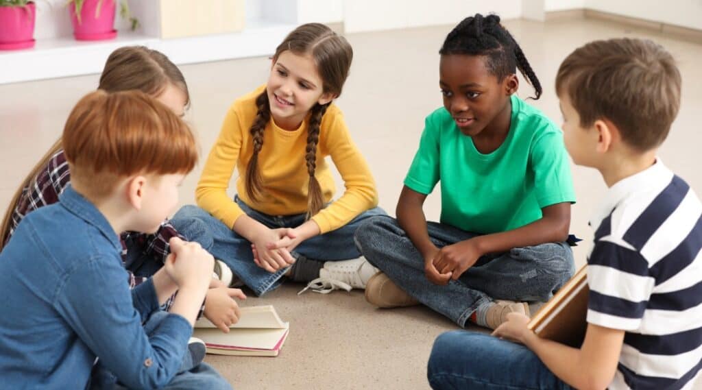 A group of elementary students sitting in a circle on the floor playing a word association game.