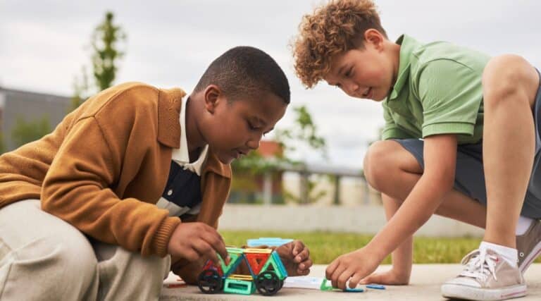 Two boys building something outside. This is an educational summer learning activity.