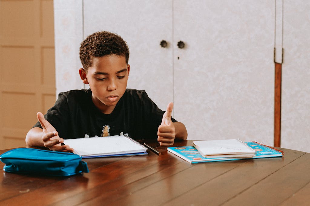 A boy engrossed in his Montessori command card question, seated at a wooden table with notebooks and a pencil case.