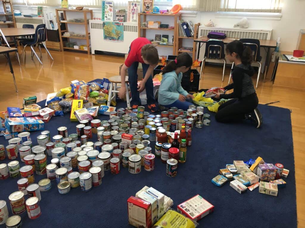 A picture of the classroom after they did a food drive and they are working together to sort and organize.