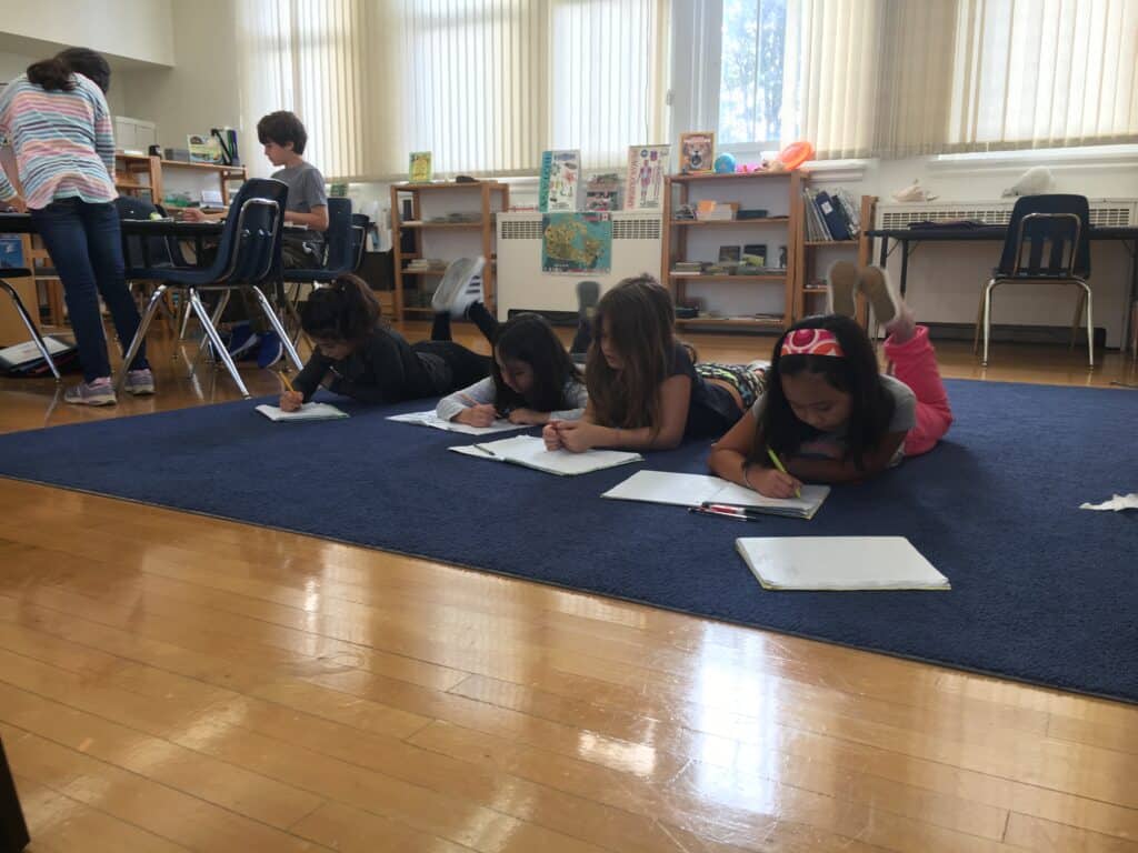 A picture of my classroom showing some students working on the floor and some at tables.