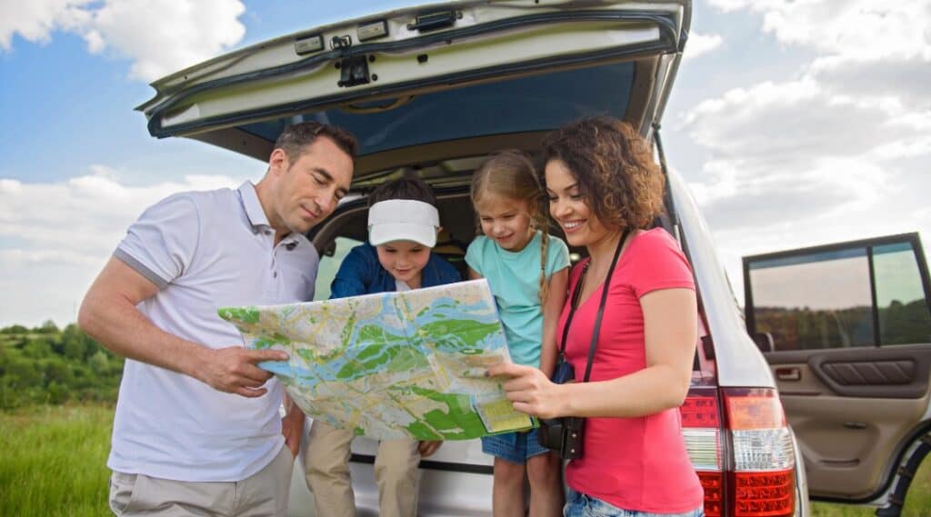 A family of 4 stops to look at a map. This can be used as a great game to play on road trips