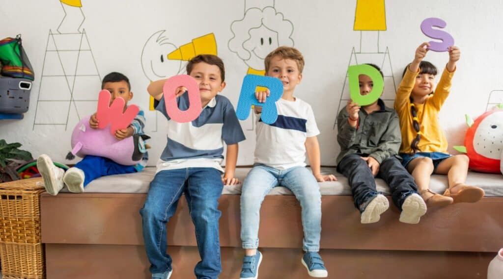 A picture of 5 young elementary students holding the letters to spell the word 'WORDS'