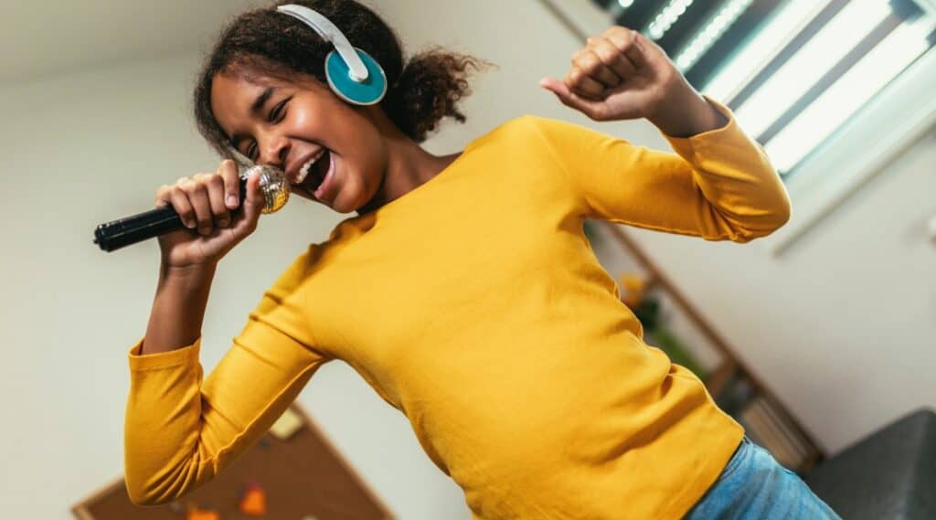 A young girl with headphones holding a microphone. She's inspired by one of the famous Montessori graduates, Beyonce.