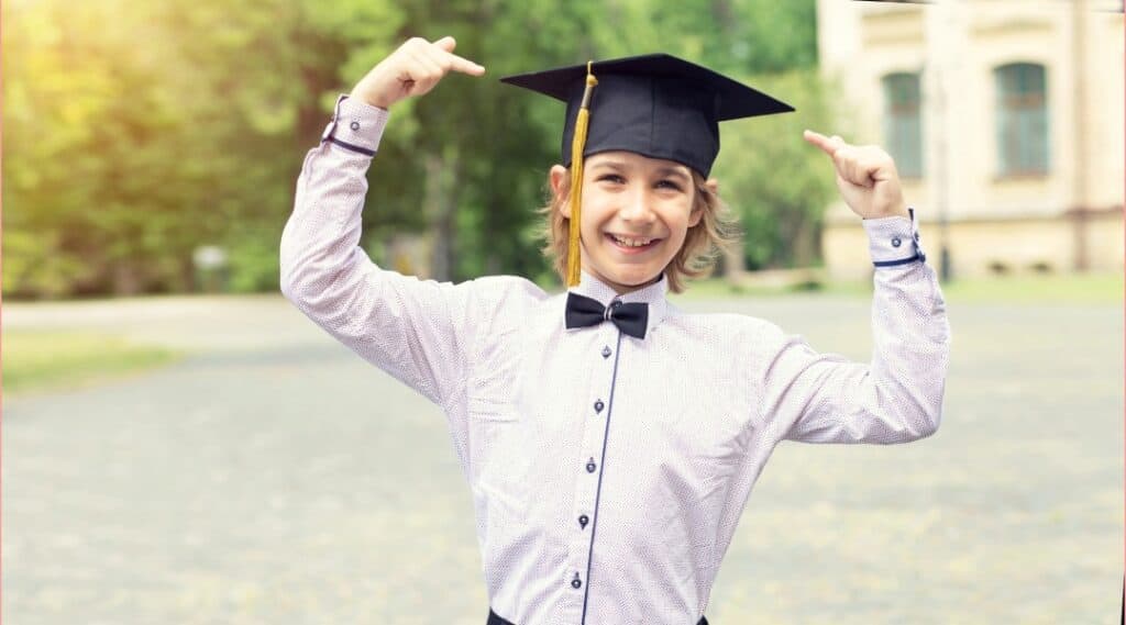 A picture of a 12 year old boy, wearing a button up shirt, a bow tie, and a graduation cap. He's looking to be the next famous Montessori graduate.