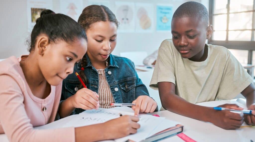 Three elementary students working together at a table.