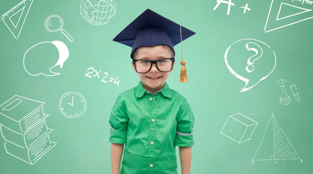 An image of an elementary aged boy wearing a green button up shirt and wearing a graduation cap.
