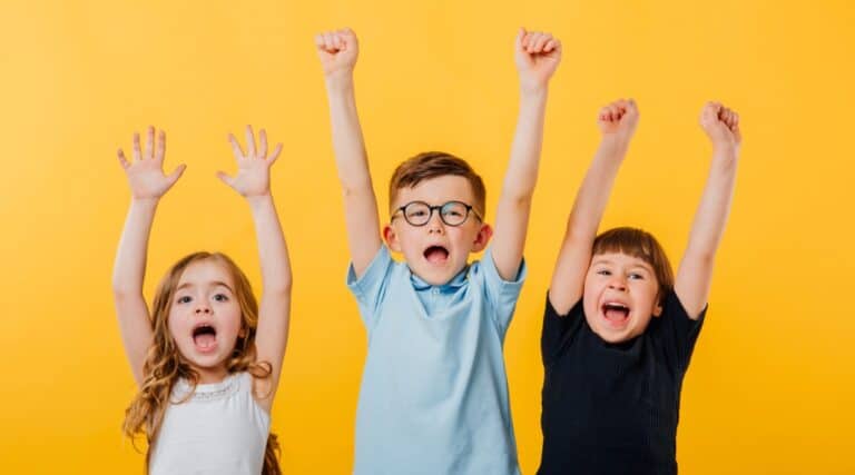 Three happy children excited to play a movement dice game called Just Roll With It.