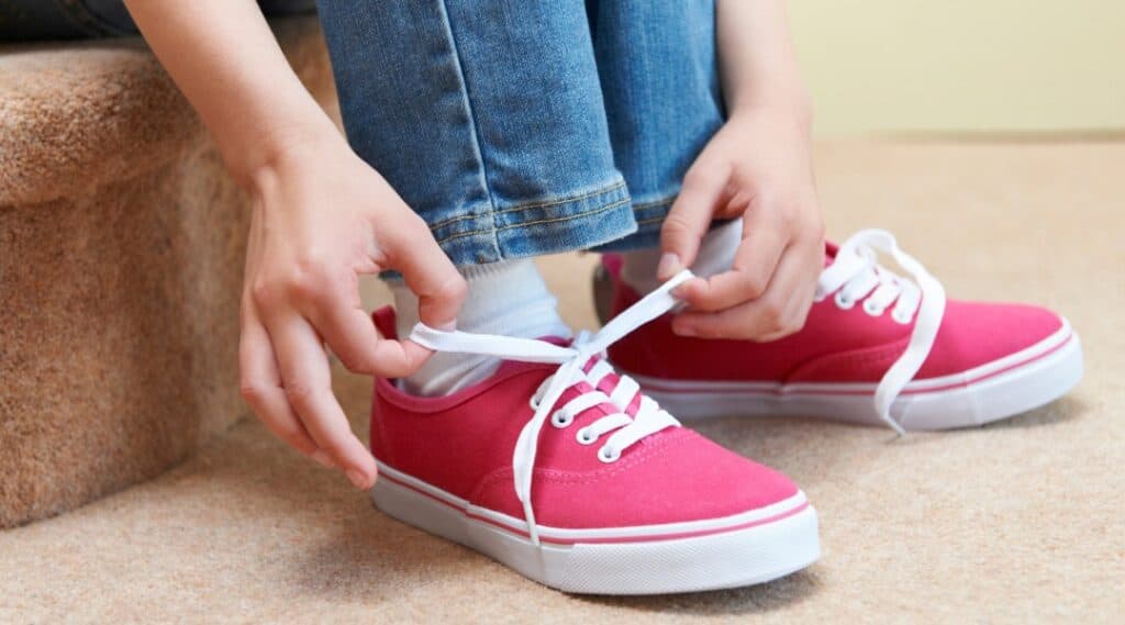 Child tying their own shoelaces to build independence and practical life skills.