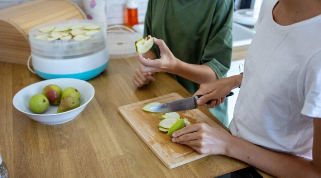Child practicing food preparation and practical life skills by cutting apples.