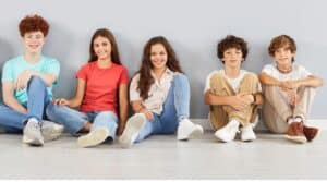 5 elementary aged kids sitting on the floor smiling at the camera; they're ready to practice some practical life skills
